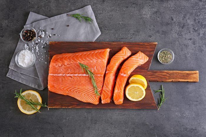 Board with fresh salmon fillet on table