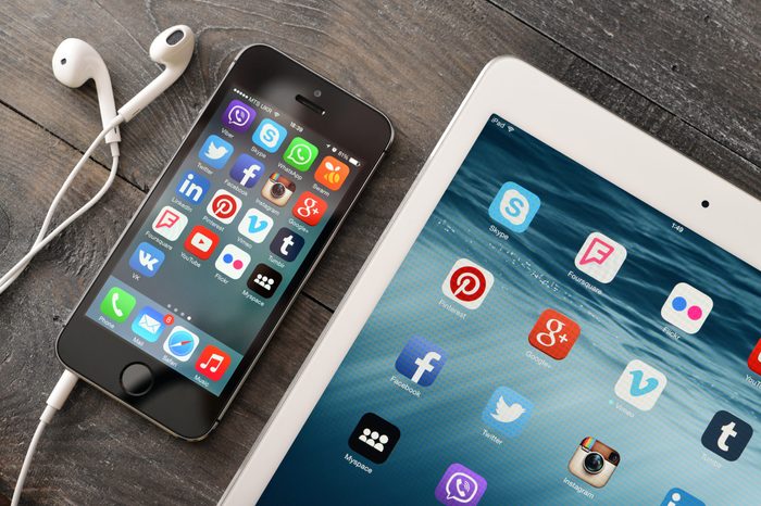 Social media icons on screen of iPad and iPhone.