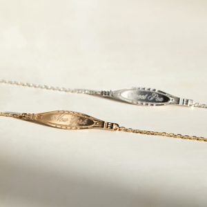 Two bracelets lie on a surface, each showcasing an engraved name, 