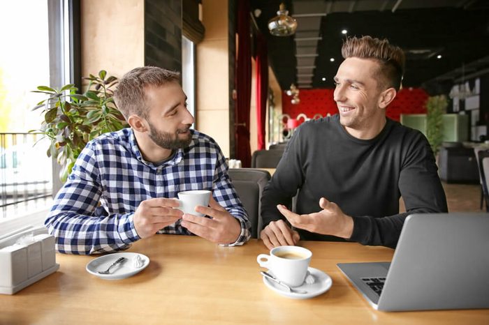 Young hipster men with coffee and laptop in cafe