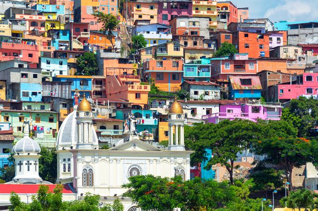 White church with a colorful slum on a hill rising above it in Guayaquil, Ecuador