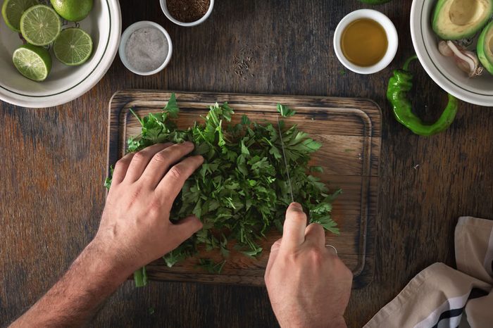 Cooking of Mexican guacamole sauce. Man preparing Mexican sauce guacamole, top view