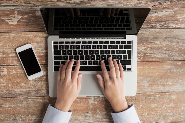 close up of hands with laptop and smartphone