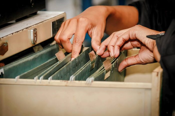 Documents in the office : Find the file in the drawer : Woman working hand searching for file in drawer, filing cabinet.