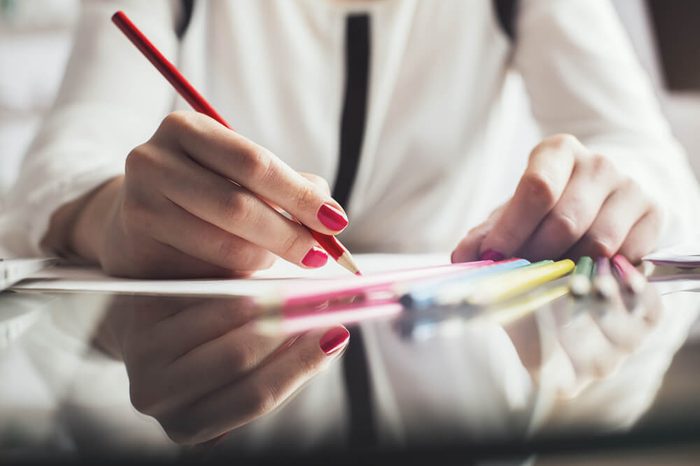 Close up of female hands at workplace drawing something with colorful pencils. Project concept