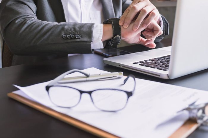 Close up of Businessman working on the desk and checking time on his wrist watch.