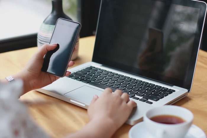 Close Up of woman hands using mobile phone and laptop computer with blank copy space screen for your advertising text message or content business in the Vintage effect.