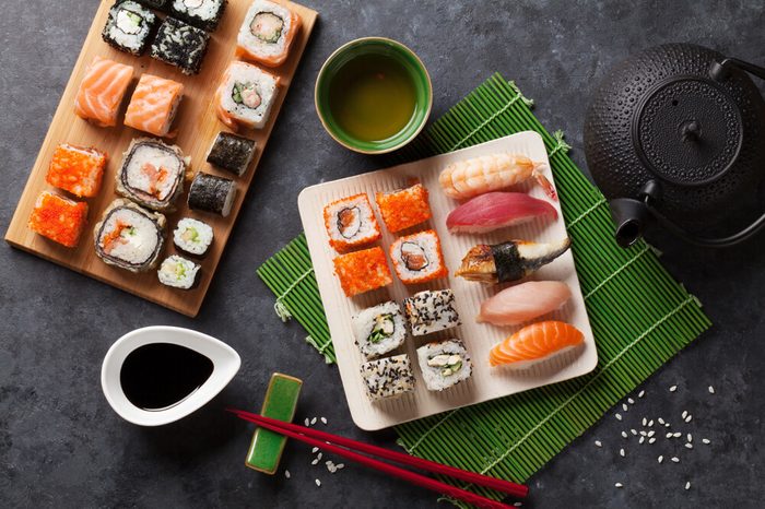 Set of sushi and maki roll and green tea on stone table. Top view