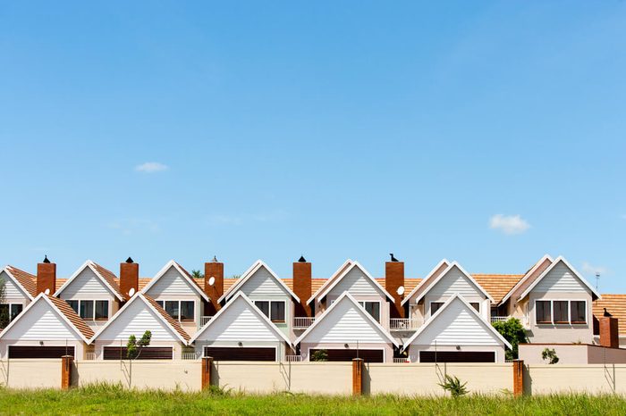 Residential fenced house complex against blue sky.