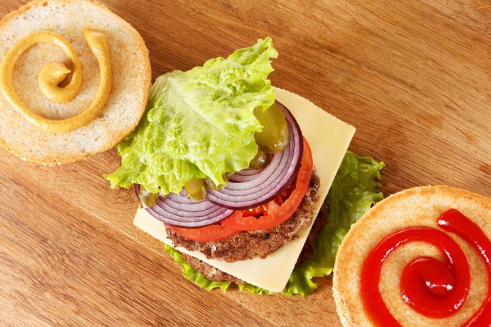 Ingredients traditional American cheeseburger. Meat, bun and vegetables close up