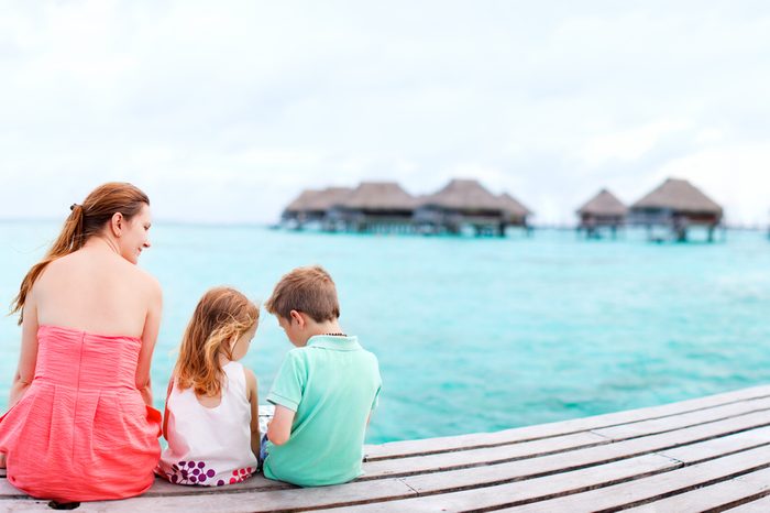 Mother and kids sitting at wooden dock enjoying ocean view