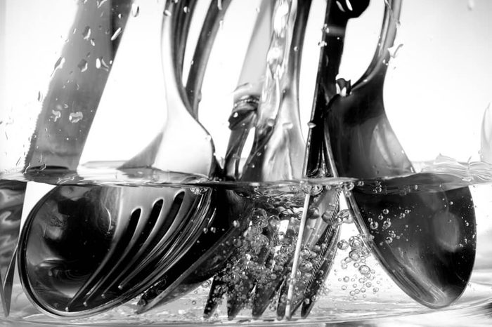 detail of the washing of cutlery under a jet of water and soap