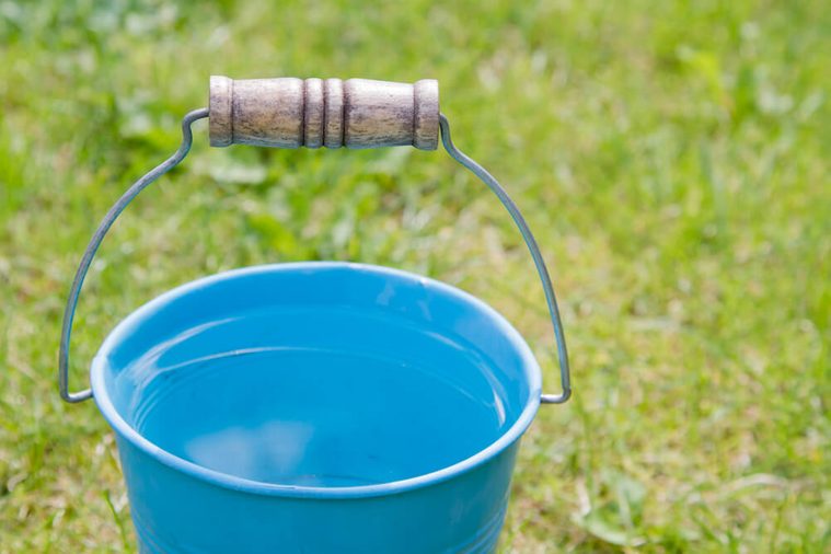 Rain falling into a full bucket of water