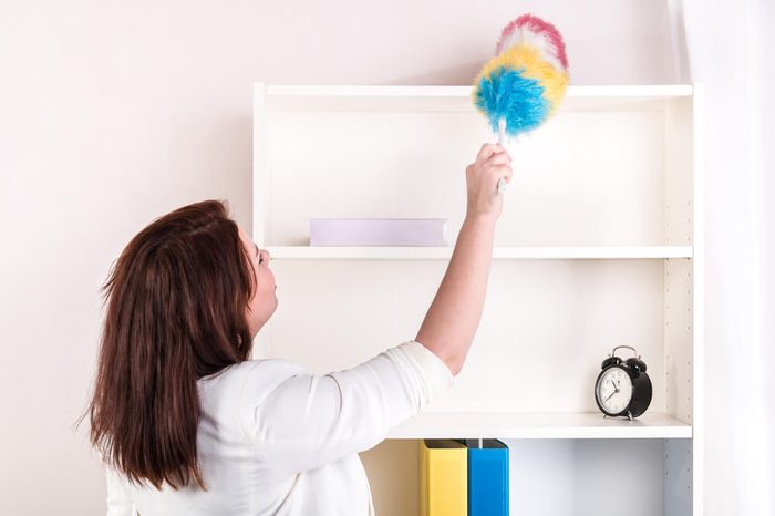 Housewife wiping dust off the shelves - studio shoot