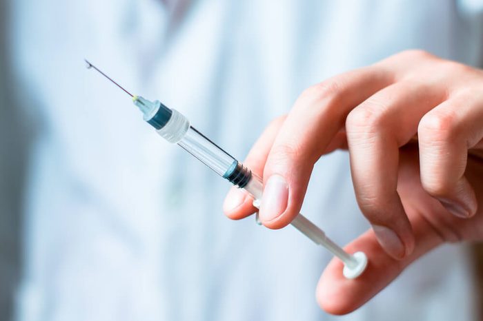Syringe, medical injection in hand, palm or fingers. Medicine plastic vaccination equipment with needle. Nurse or doctor. Liquid drug or narcotic. Health care in hospital.