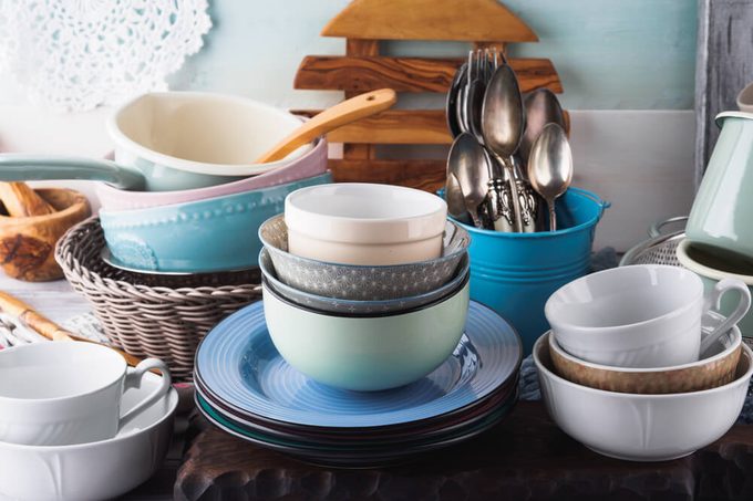 Ceramic and enamel crockery tableware on wooden background. Pastel vintage colors