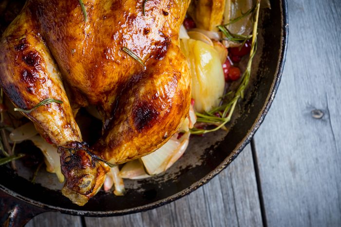 Roasted chicken in pan on the rustic wooden background. Selective focus.