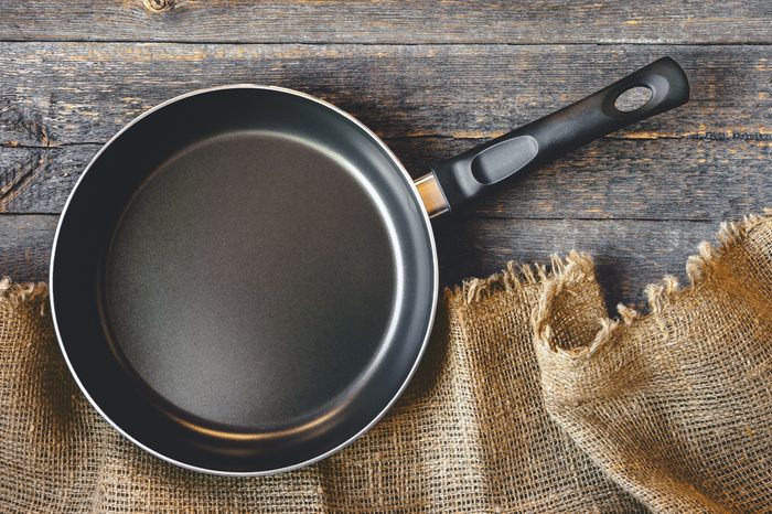 An empty pan on a wooden table and tablecloth