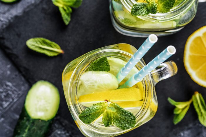 Above view of two mason jar with detox water on dark concrete background. Summer drink with cucumber, lemon and mint. Copy space. Top view or flat lay