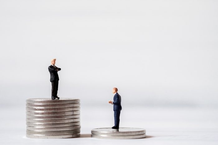 Miniature business people stand on pile of money coin. Cash is king financial concept and more buy power.