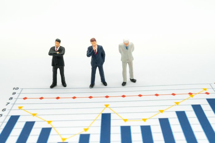 Miniature People: Business man looking at analyst graph with copy space using as background money, financial, business concept.