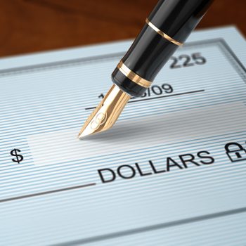 Writing a check with an old fashioned fountain pen on a wooden table