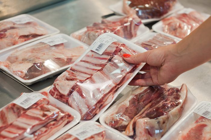Image of packaged meat with woman hand in the supermarket