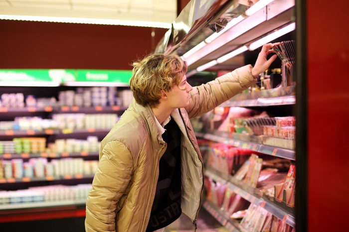 Man shopping in supermarket, reading product information