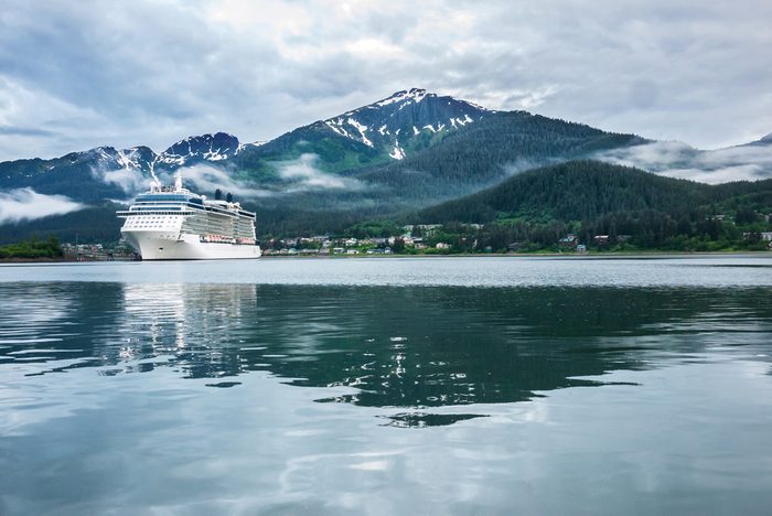 Cruise ship at a port in Juneau, Alaska with snow capped mountain and low lying fog in the background