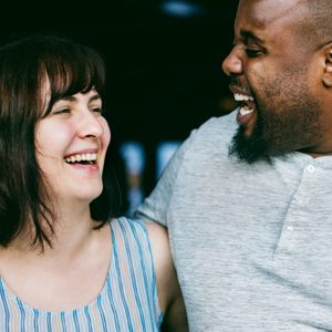Two people laugh together, sharing a joyful moment in a casual indoor setting.
