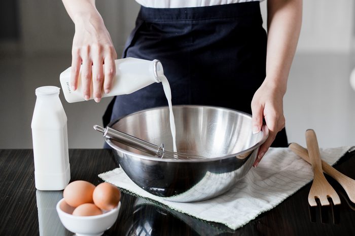 Pouring milk in a bowl of flour
