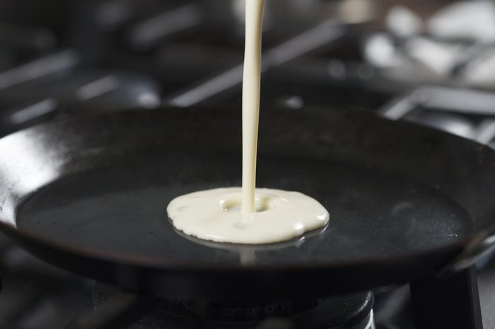 preparing blini or crepes batter pouring on hot pan, 4k photo