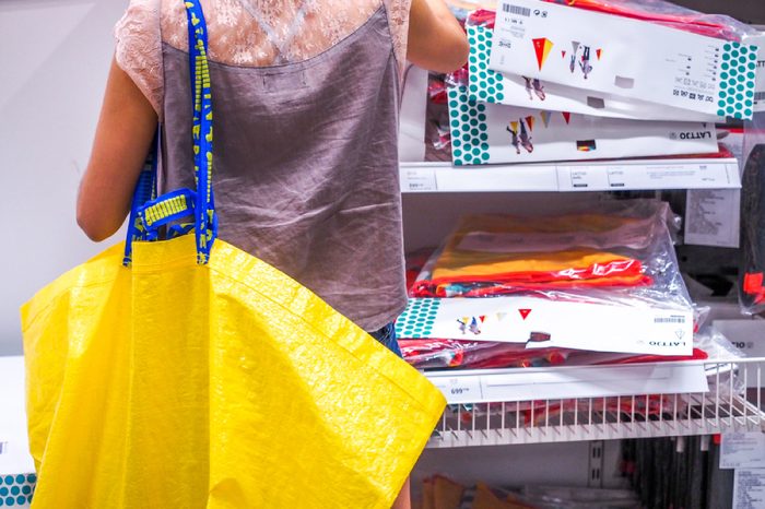 The woman shopping with Big yellow shopping bags in IKEA Store. IKEA is the world's largest furniture retailer, founded in Sweden in 1943