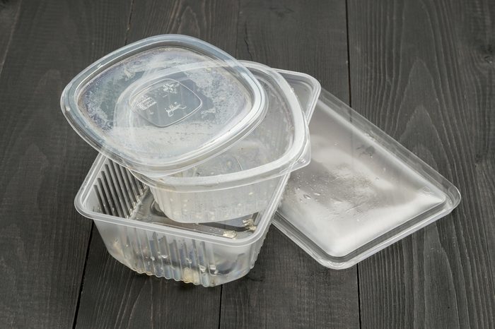 Dirty plastic food container on dark wooden background. Used food box as Garbage. Environmental pollution concept