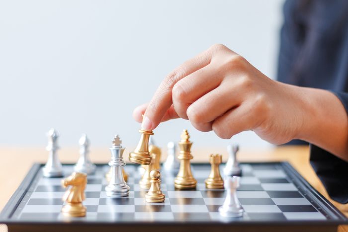 Close up shot hand of business woman moving golden chess to defeat a silver king chess on white and black chess board for business challenge competition winner and loser concept, selective