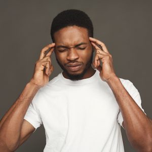 Headache. Concentrated pensive black man thinking about something, holding fingers on temple, white studio background