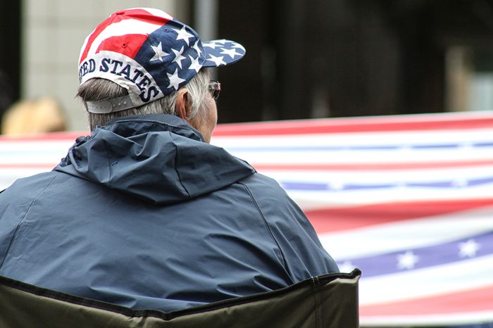 Red, white and blue hat on woman who watches the American flag go by at a July 4th parade.