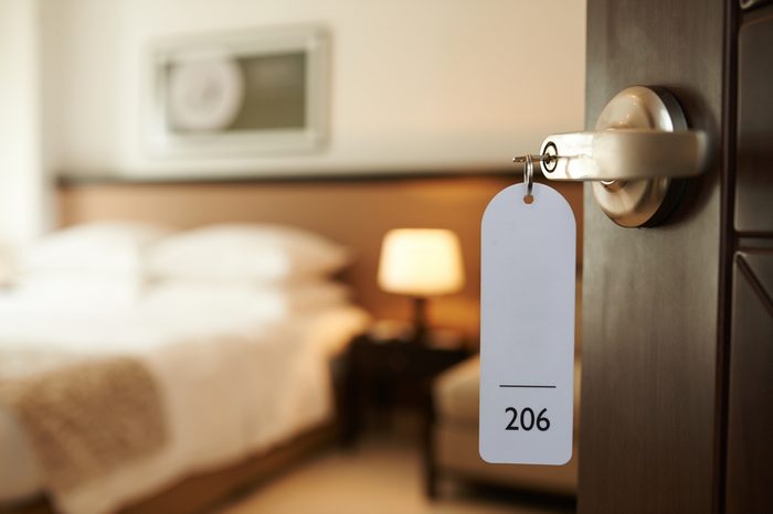 Opened door of hotel room with key in the lock