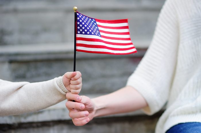 Young woman and little child holding american flag. Independence Day concept. Family together