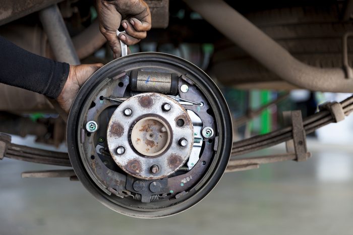 mechanic hands are fixing old rusted drum brake and disc brake mechanism of car by hand 