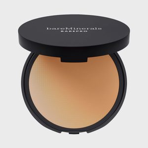 Compact powder sits open, revealing a smooth tan surface. The lid reads 