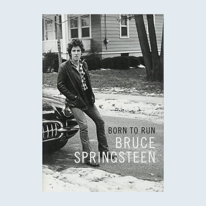 Man stands beside a vintage car on a snowy street, wearing a leather jacket. Text: 