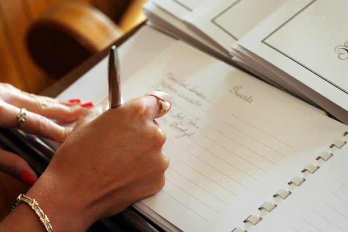 Womans hand signing a guest book with a pen