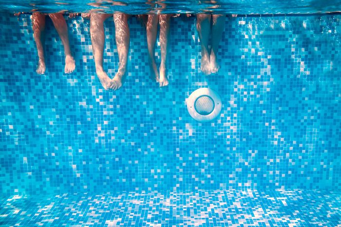 Children's and adults legs underwater in the swimming pool