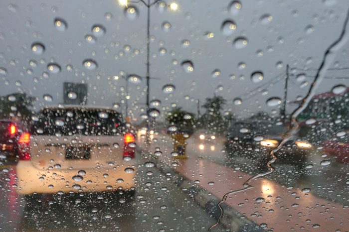 Road view through car window with rain drops driving in rain.Traffic view from car windscreen in rain.Driving in rain.Selective focus