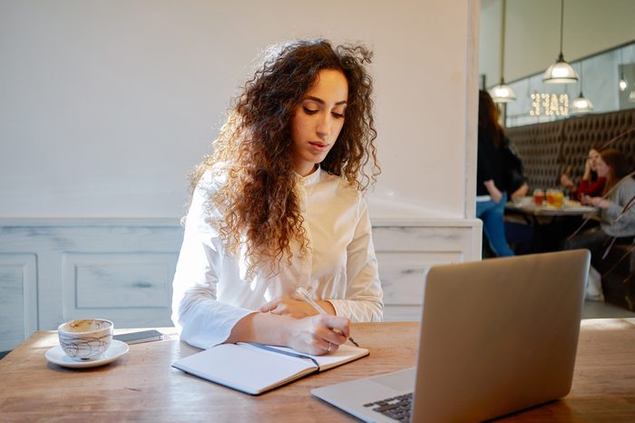 Young attractive business woman holds a job interview in a cafe during the lunch break. businesswoman searching for information on the Internet and makes notes in a notebook