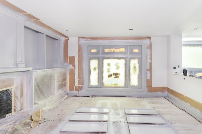 Walls and windows masked with paper and plastic as trim and shelves are spray painted