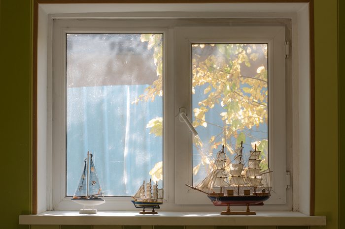 a window in the bedroom, a collection of ship models, a view of the street with trees