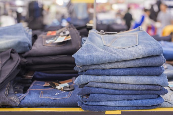 Advertise concept. Lot of different blue jeans Blue jeans on tables in clothes store on background blur supermarket. (lens blur effect)