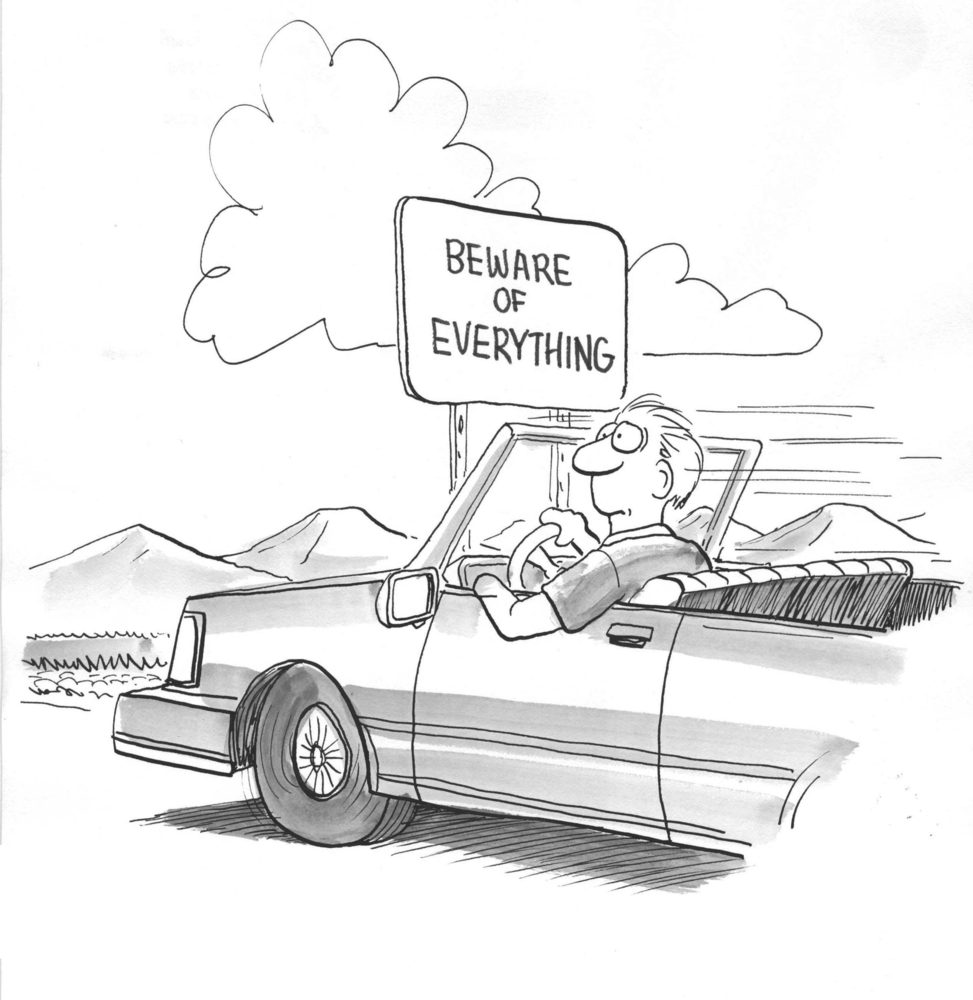 A person drives past a sign stating "BEWARE OF EVERYTHING" in a mountainous, open landscape.